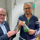 Los científicos Chris Howe (izquierda) y Paolo Bombelli (derecha) sostienen su unidad de energía basada en algas y un frasco con una solución de cianobacterias
